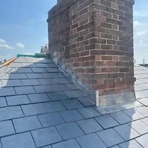 a brick chimney on a roof with a blue sky in the background